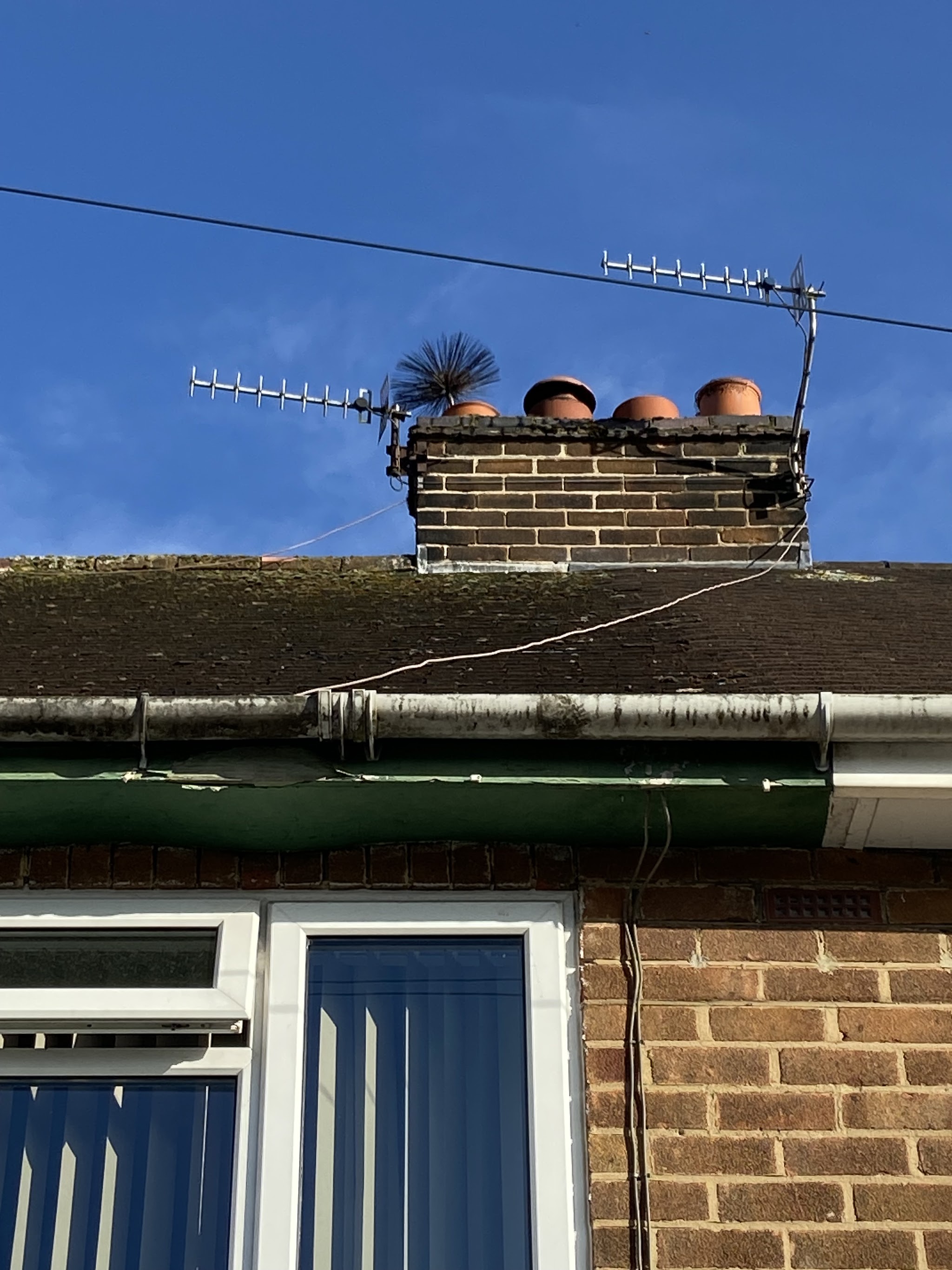 Brick chimney stack with four pots against a blue sky