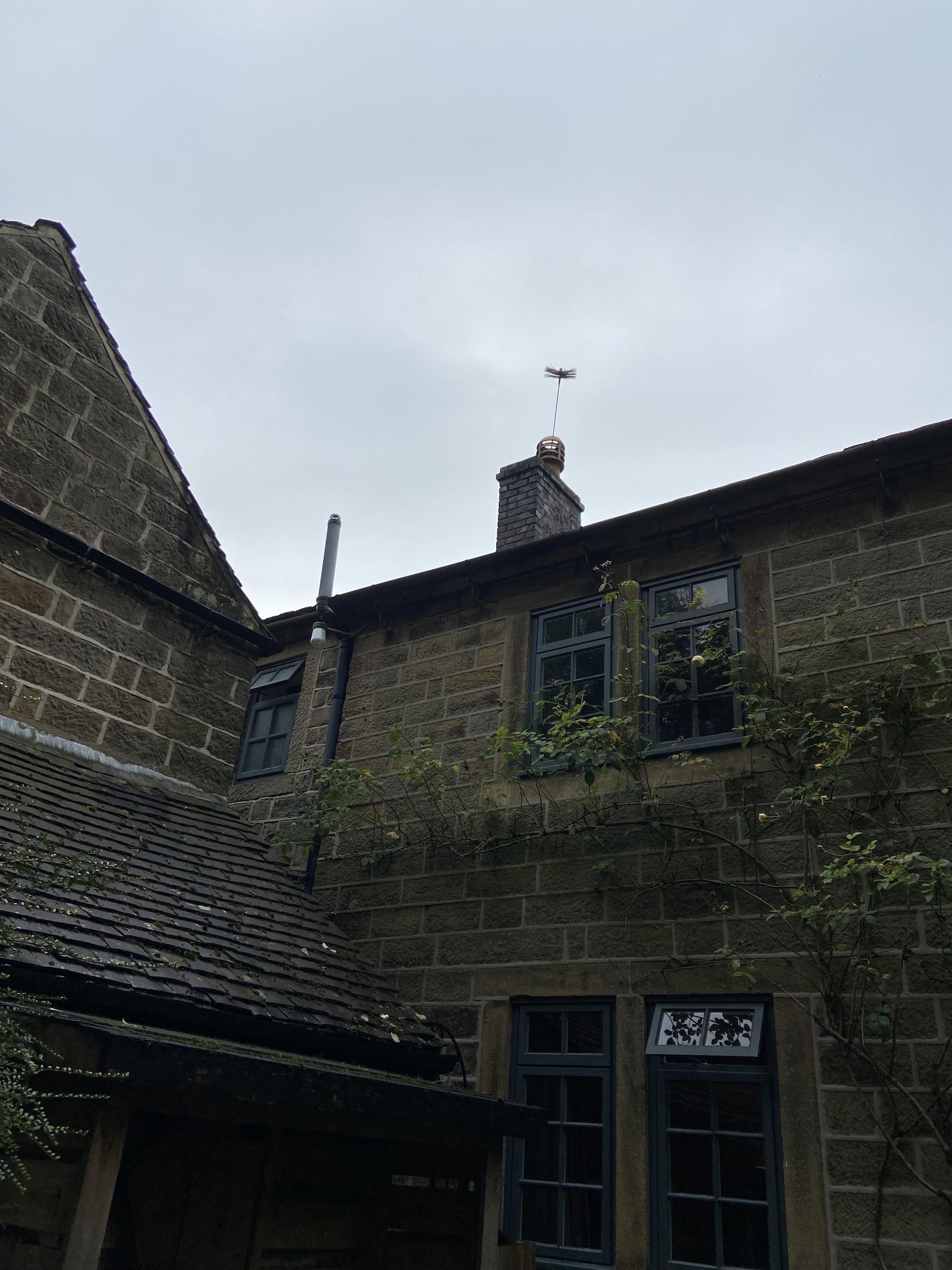 Bretburn's sweeping brush poking out of the chimney of a stone cottage