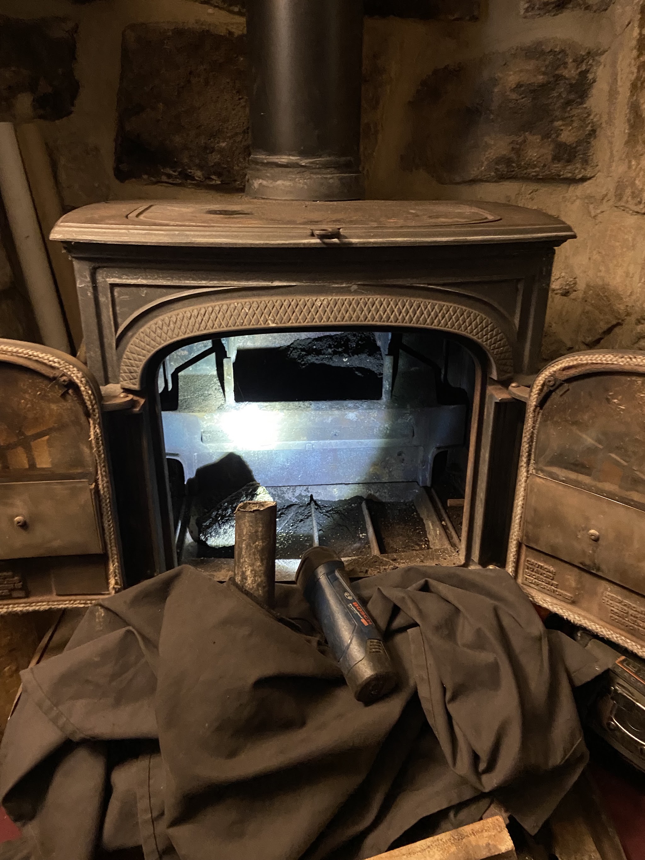 Cast-iron stove in a stone fireplace, protected by a dust sheet